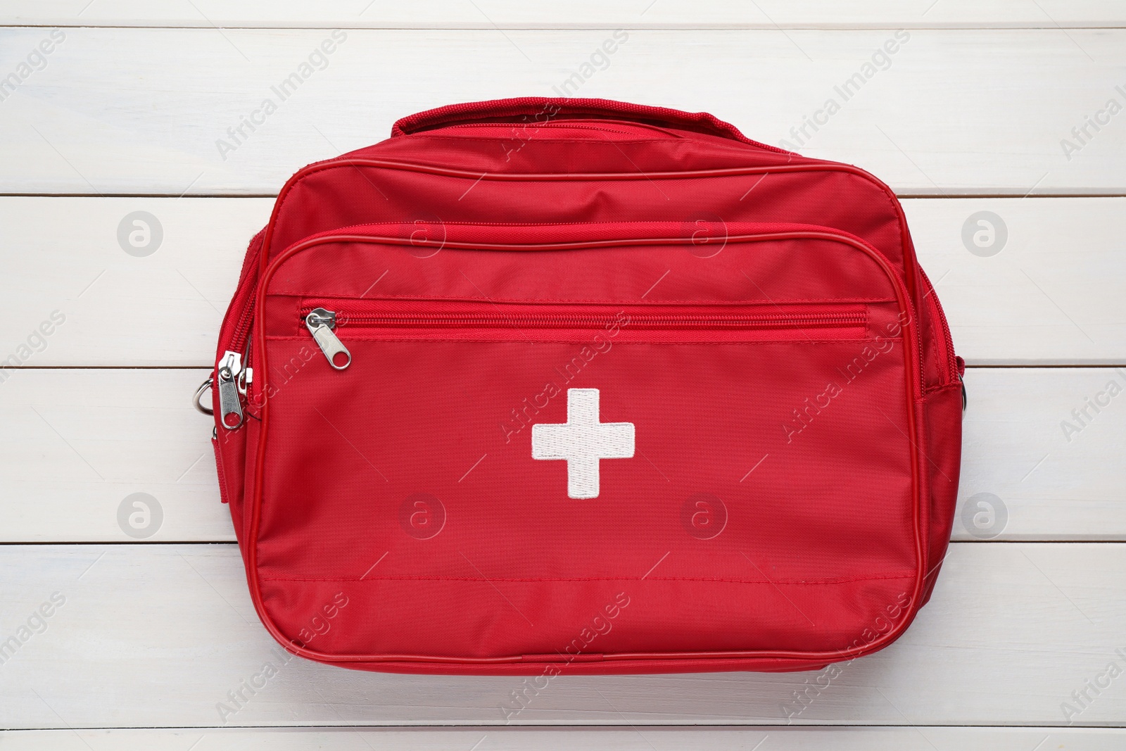 Photo of First aid kit bag on white wooden background, top view