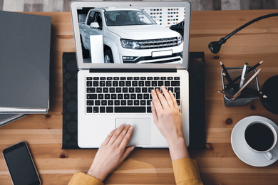 Image of Buying online. Woman choosing car using laptop, top view