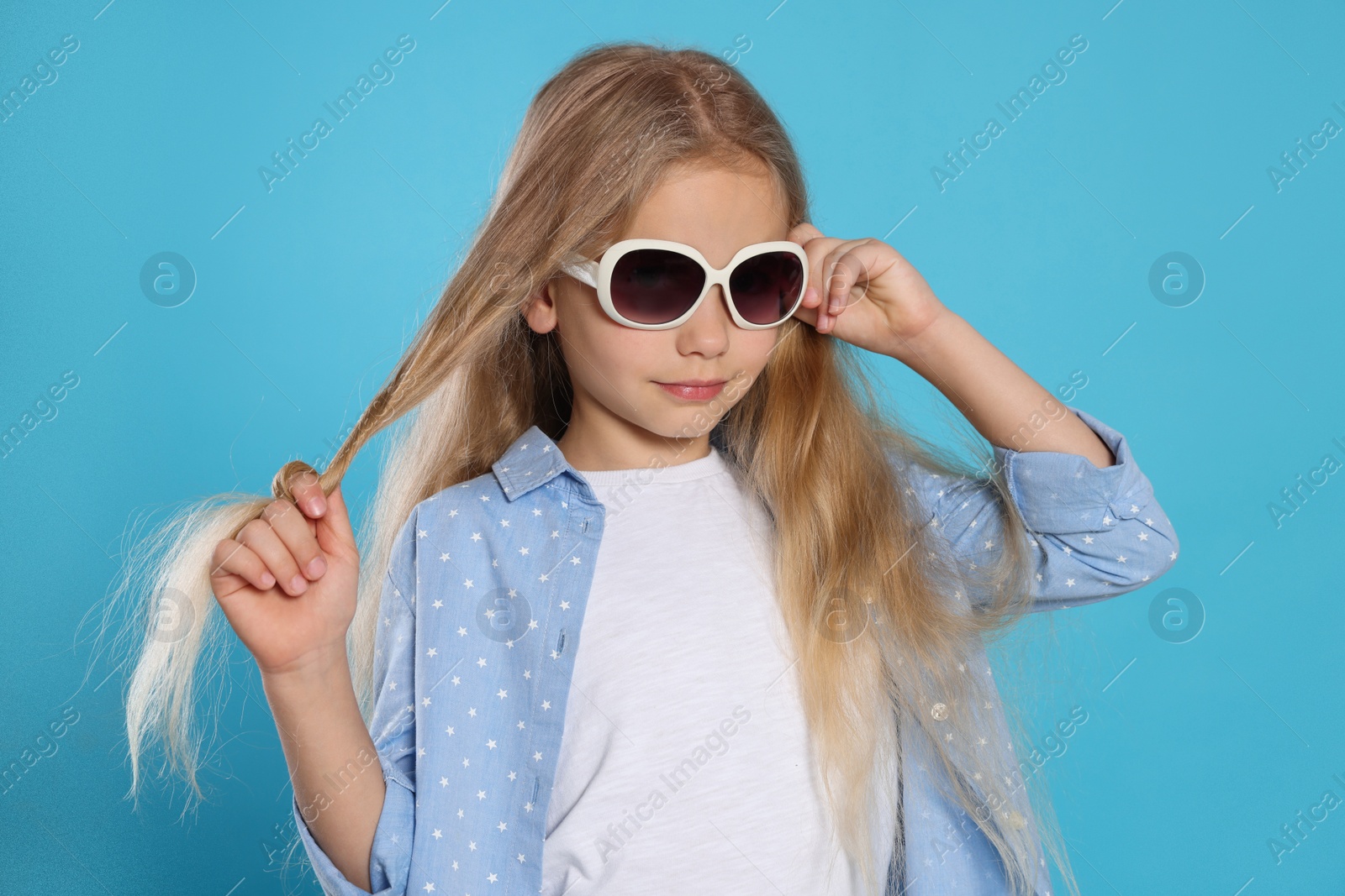 Photo of Girl in stylish sunglasses on light blue background