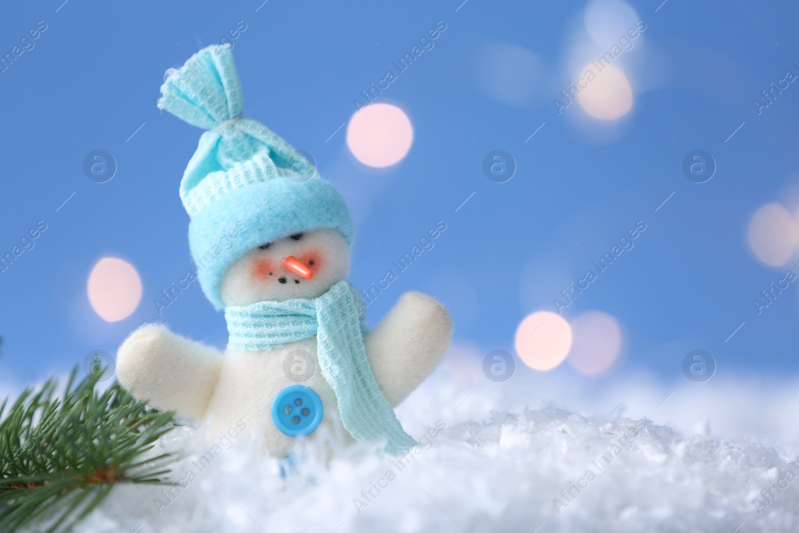 Photo of Cute toy snowman and fir branch on snow against blurred background. Space for text