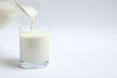 Pouring milk into glass on white background