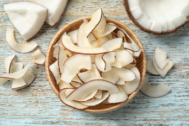 Tasty coconut chips on light blue wooden table, flat lay