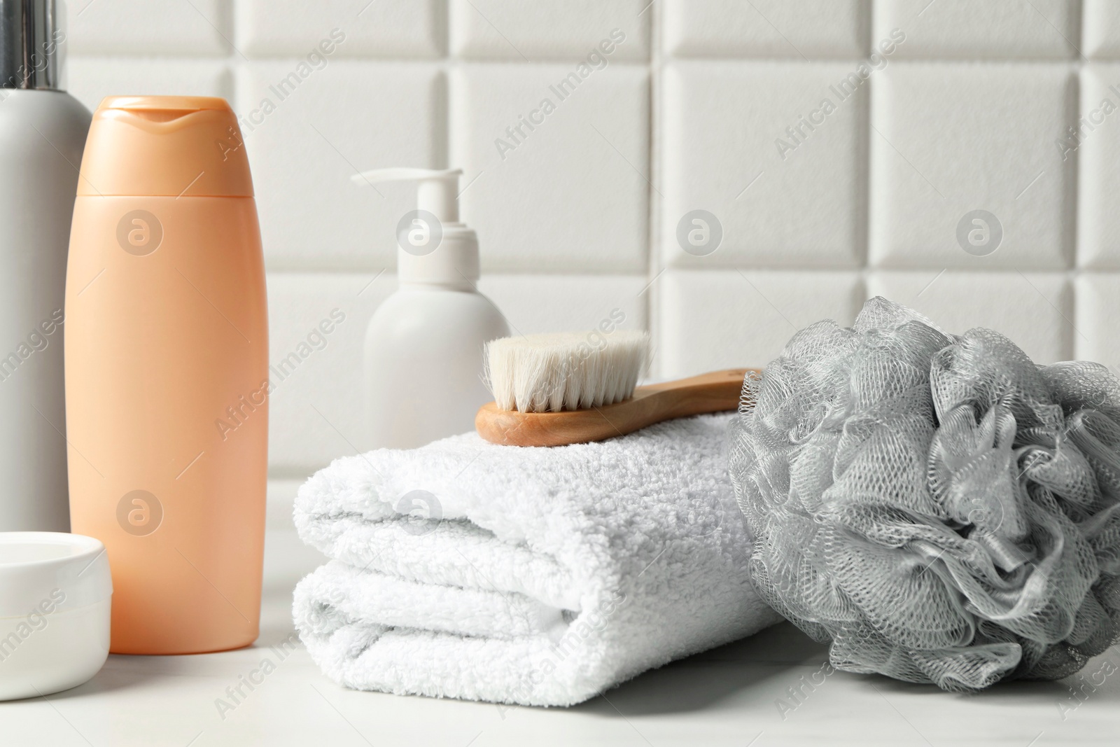 Photo of Bath accessories and personal care products on white table near tiled wall, closeup