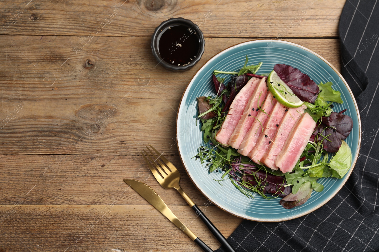 Photo of Pieces of delicious tuna steak with salad served on wooden table, flat lay. Space for text