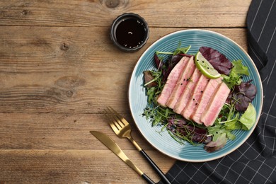 Pieces of delicious tuna steak with salad served on wooden table, flat lay. Space for text