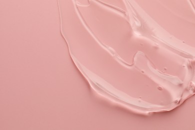 Photo of Sample of clear cosmetic gel on pink background, top view. Space for text