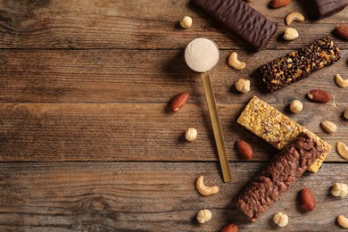 Different tasty bars, nuts and scoop of protein powder on wooden table, flat lay. Space for text