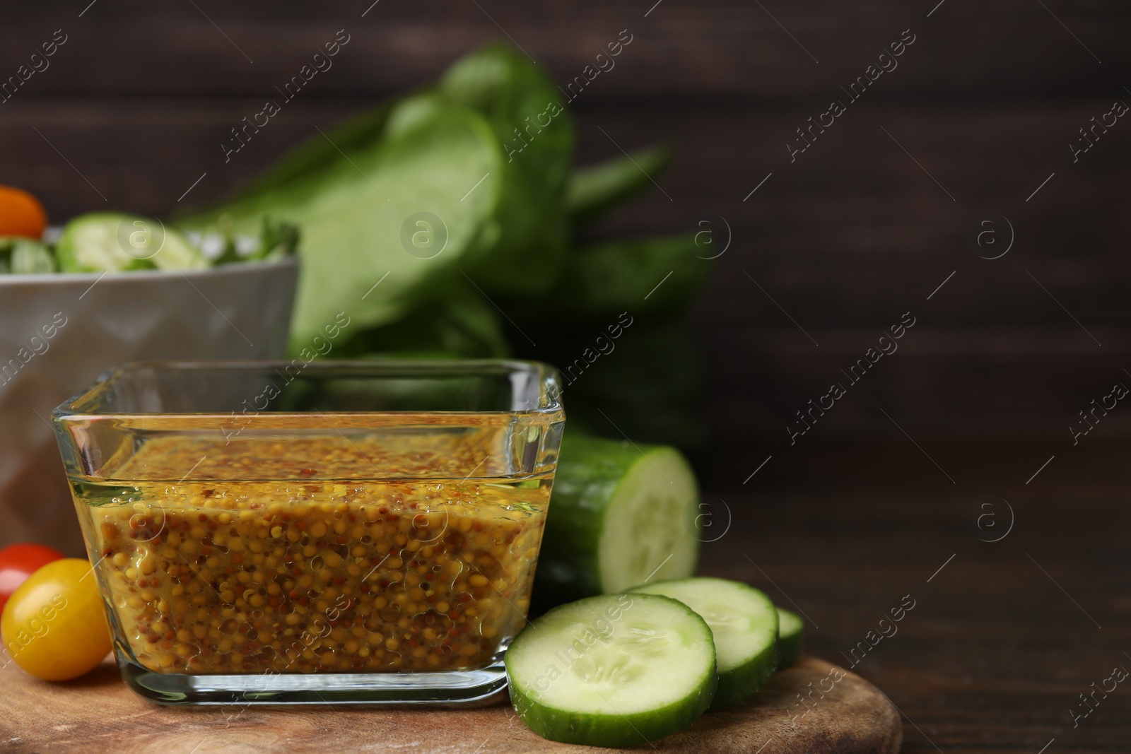 Photo of Tasty vinegar based sauce (Vinaigrette) in bowl, cucumber and tomatoes on wooden table, closeup. Space for text