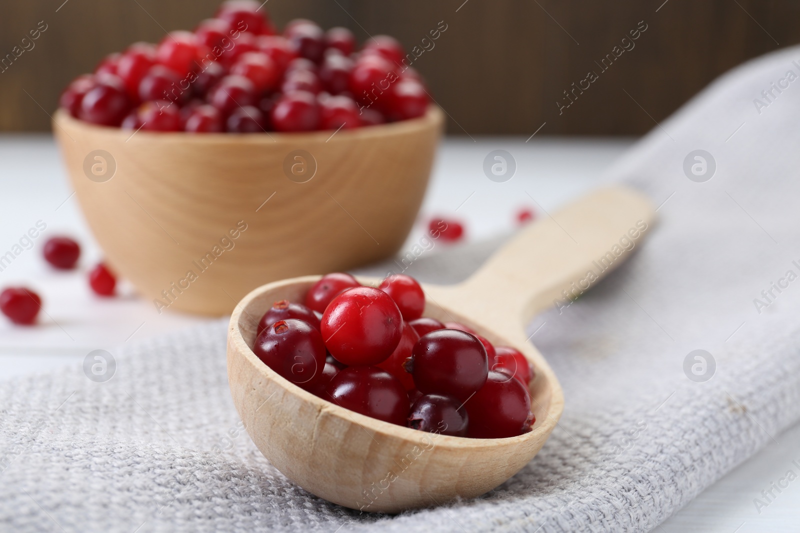 Photo of Spoon with fresh ripe cranberries on table, closeup