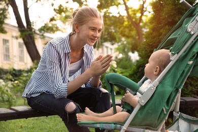 Photo of Teen nanny with cute baby in stroller playing in park