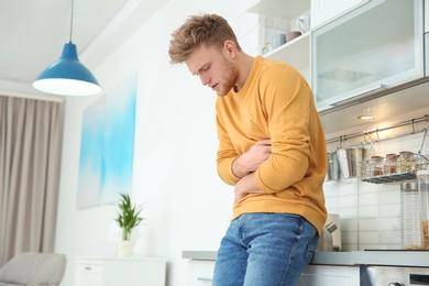 Photo of Young man having nausea in kitchen. Space for text