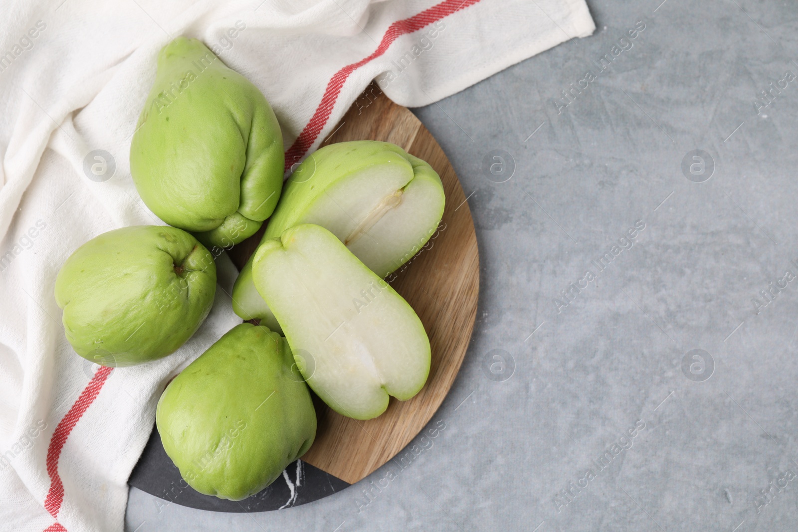 Photo of Cut and whole chayote on gray table, top view. Space for text