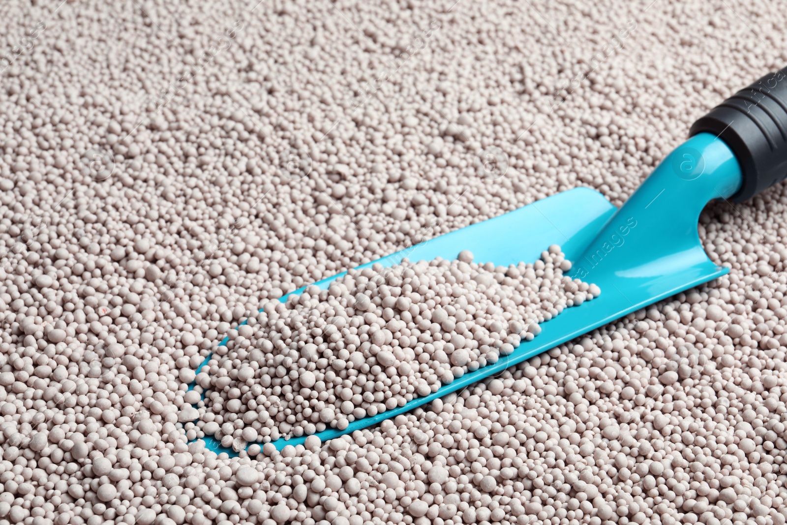 Photo of Metal trowel on chemical fertilizer, closeup. Gardening season