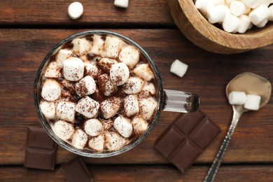 Cup of aromatic hot chocolate with marshmallows and cocoa powder served on wooden table, flat lay