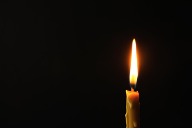 Burning candle on dark background, space for text. Symbol of sorrow