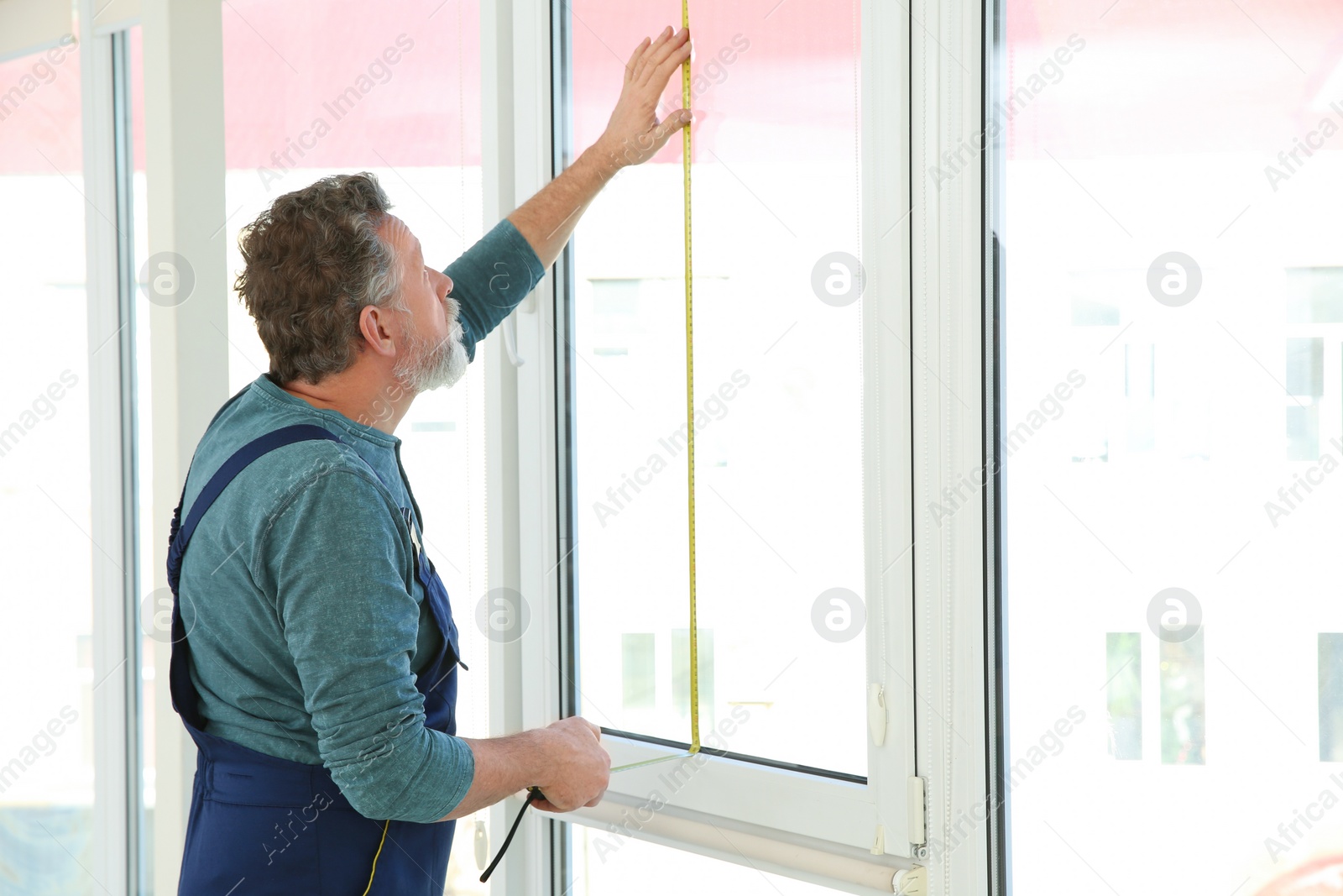 Photo of Service man measuring window for installation indoors