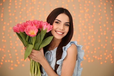 Portrait of smiling young girl with beautiful tulips on blurred background. International Women's Day