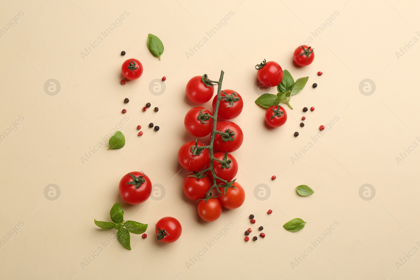 Photo of Fresh cherry tomatoes, basil leaves and pepper grains on beige background, flat lay