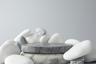 Photo of Presentation for product. Stone podium and pebbles on light grey background. Space for text