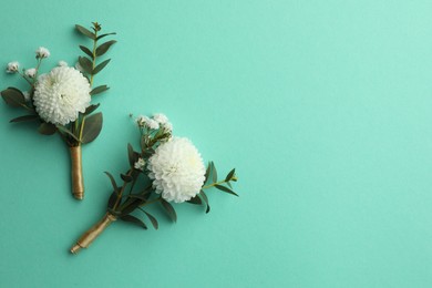 Small stylish boutonnieres on turquoise background, flat lay. Space for text