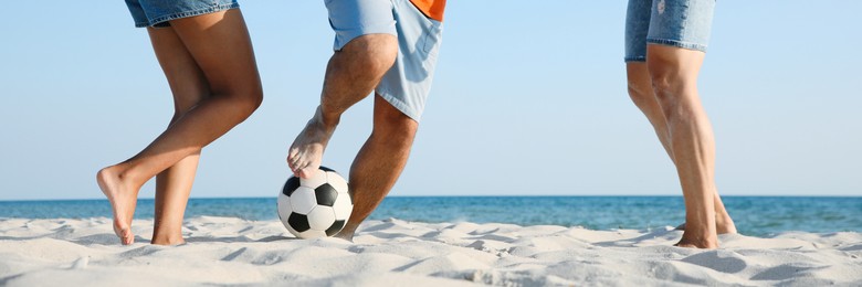 Image of Group of friends playing football on sandy beach, closeup. Banner design