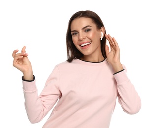 Happy young woman listening to music through wireless earphones on white background