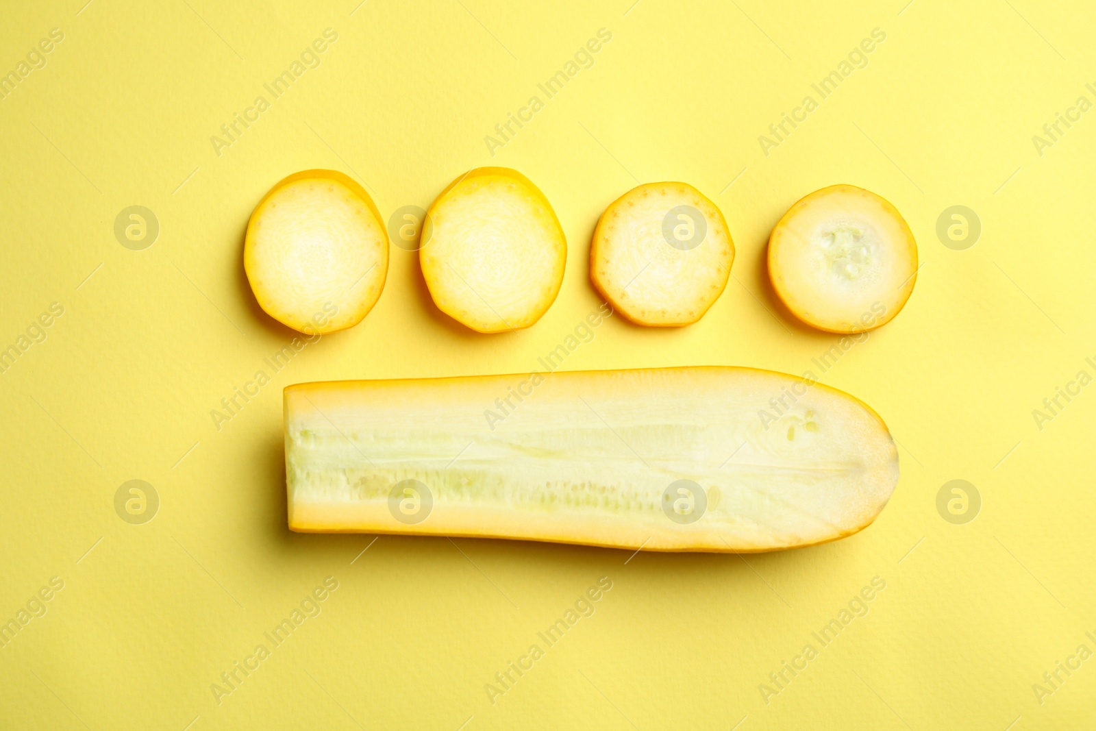 Photo of Fresh ripe cut zucchini on yellow background, flat lay