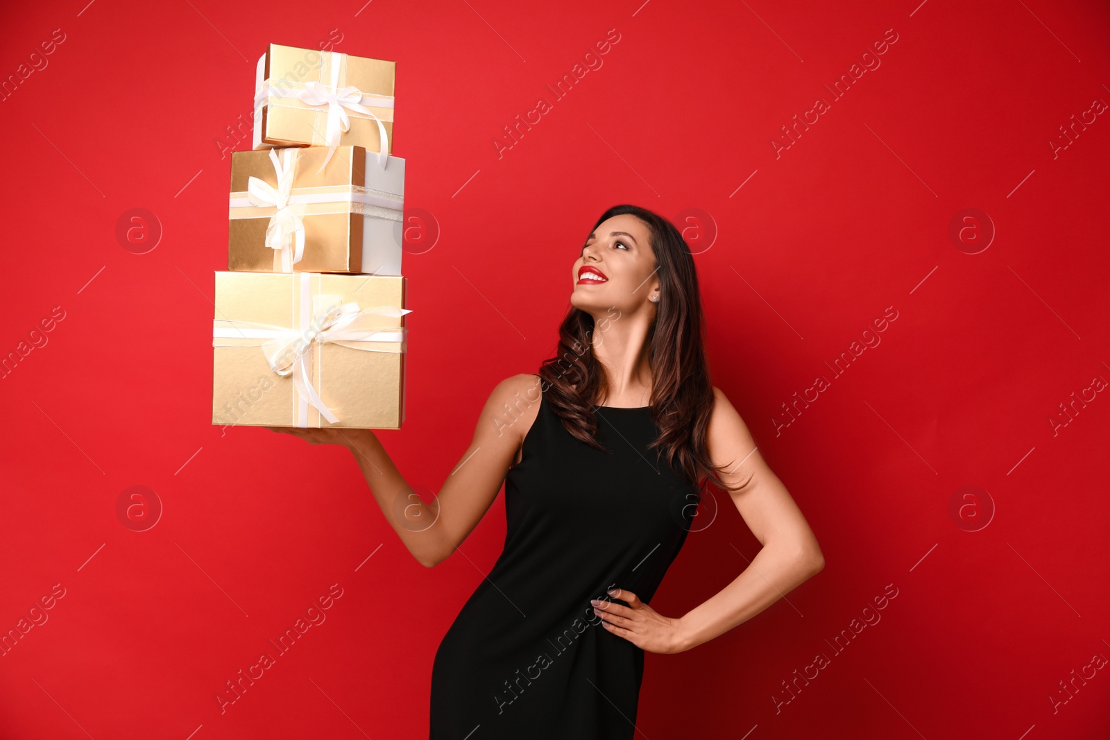 Photo of Beautiful woman with Christmas gifts on red background