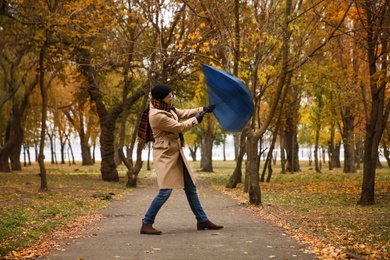 Photo of Man with blue umbrella caught in gust of wind outdoors