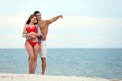 Photo of Happy young couple spending time together on sea beach. Space for text