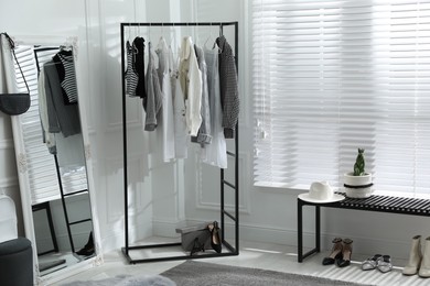 Rack with stylish women's clothes and large mirror in dressing room. Interior design