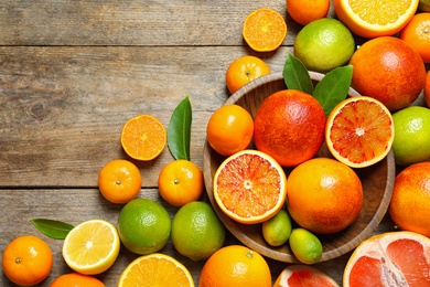 Flat lay composition with different citrus fruits and space for text on wooden background