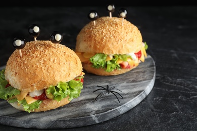 Photo of Cute monster burgers served on black table. Halloween party food