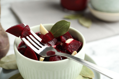 Pickled beets with garlic in bowl on table, closeup