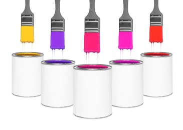 Image of Brushes with colorful paints in air over cans on white background