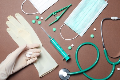 Doctor in sterile glove with medical items on color background, top view