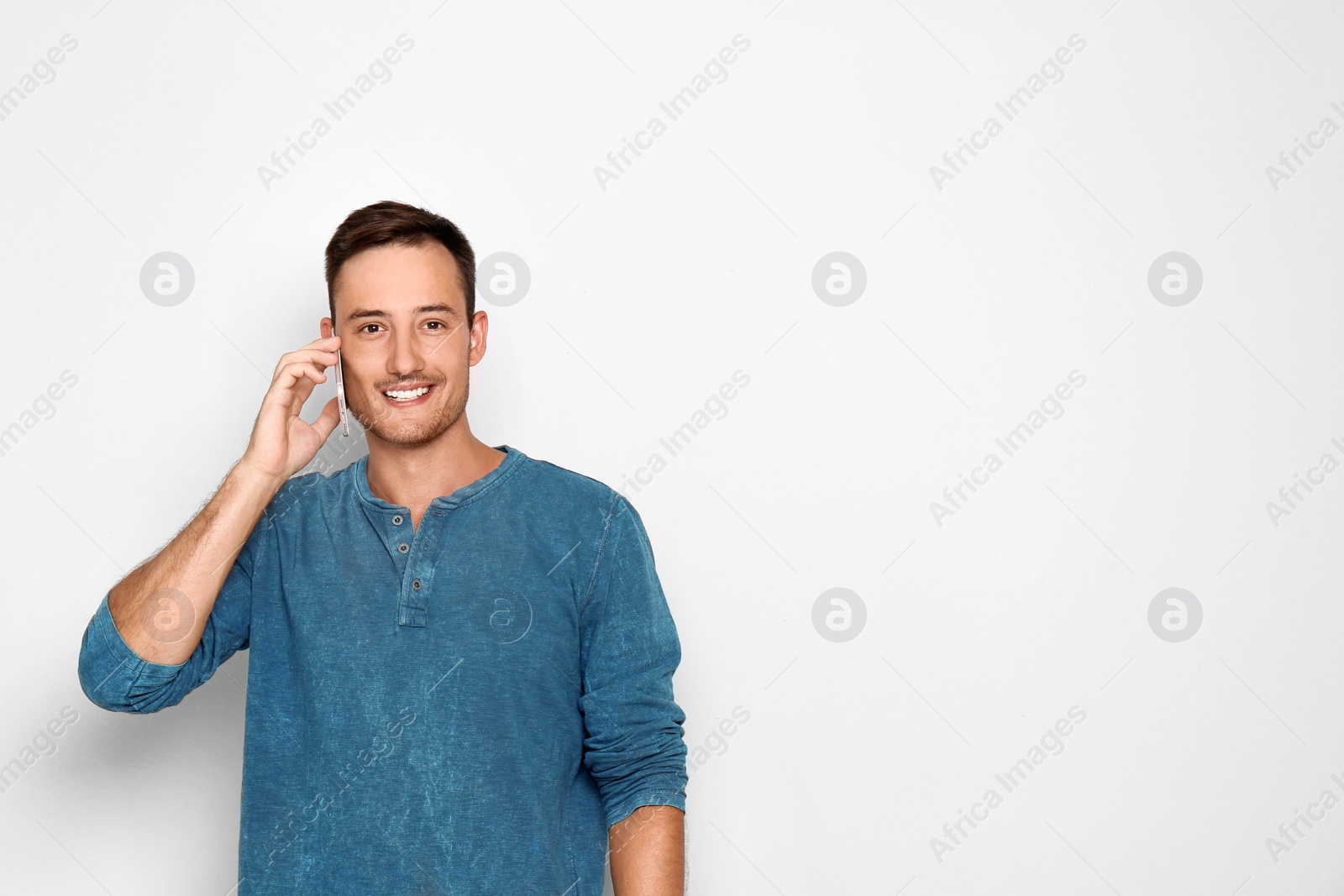 Photo of Young man talking on phone against white background. Space for text