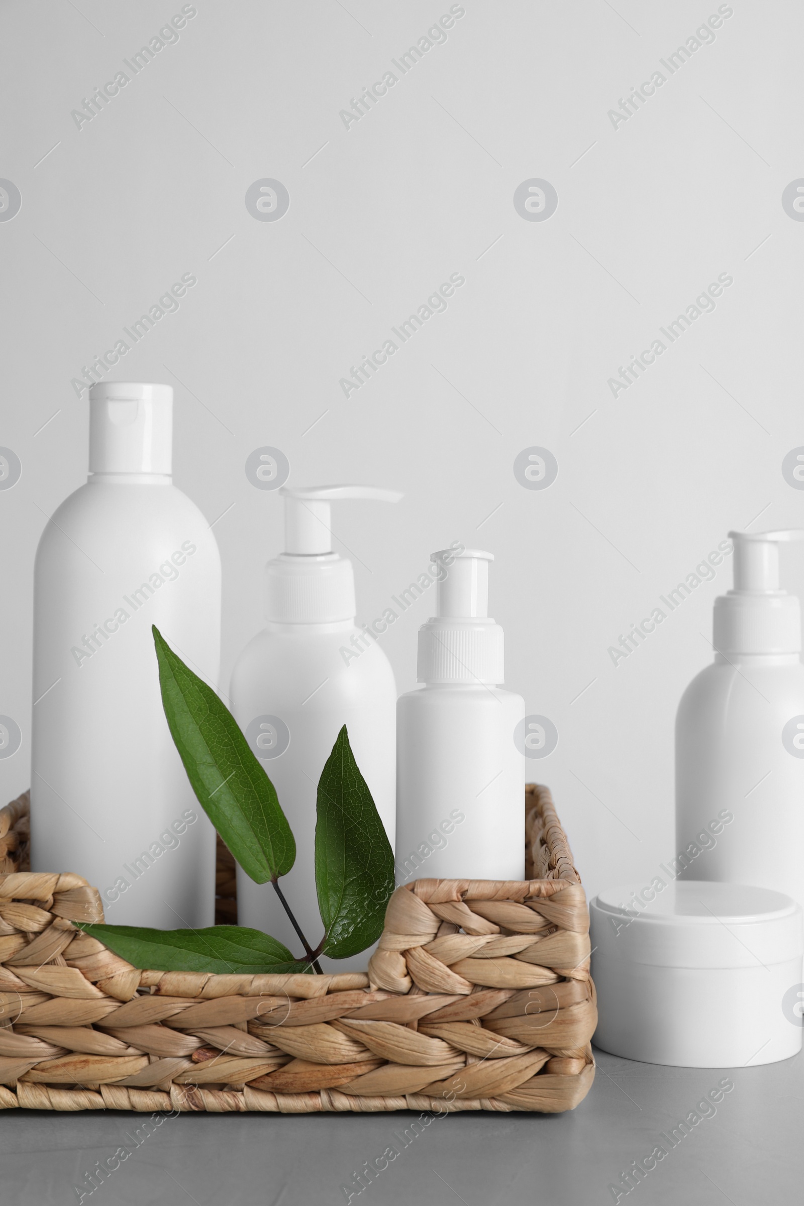 Photo of Different cosmetic products and leaves on grey table
