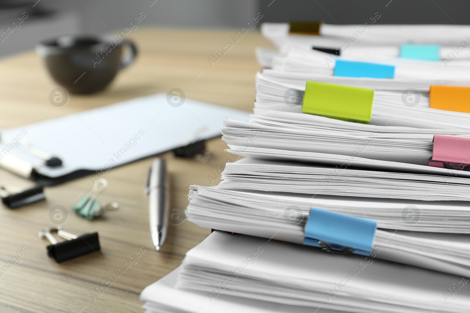 Photo of Stack of documents with binder clips and pen on wooden table, closeup view