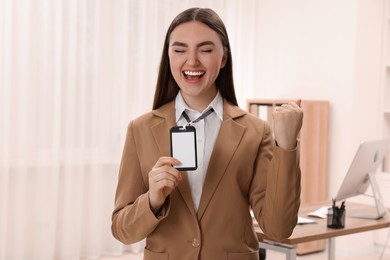 Happy woman with blank badge in office