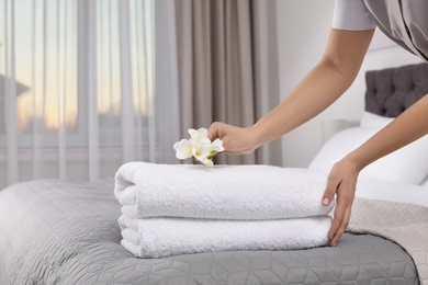 Maid putting flowers on fresh towels in hotel room, closeup