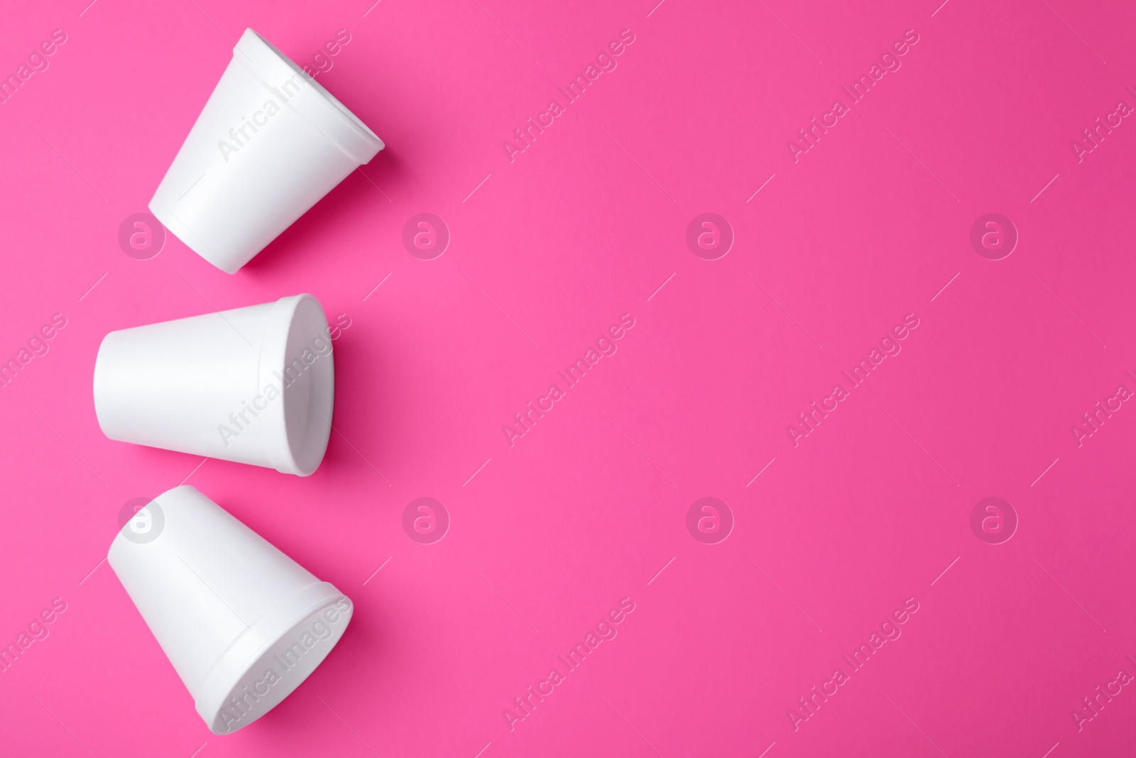 Photo of White styrofoam cups on pink background, flat lay. Space for text