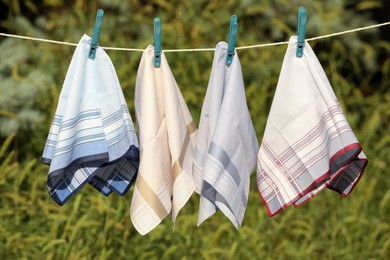 Photo of Many different handkerchiefs hanging on rope outdoors