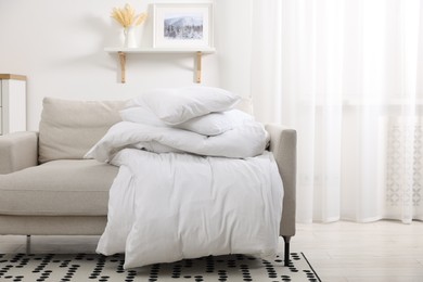 Photo of Soft pillows and duvet on sofa indoors, space for text