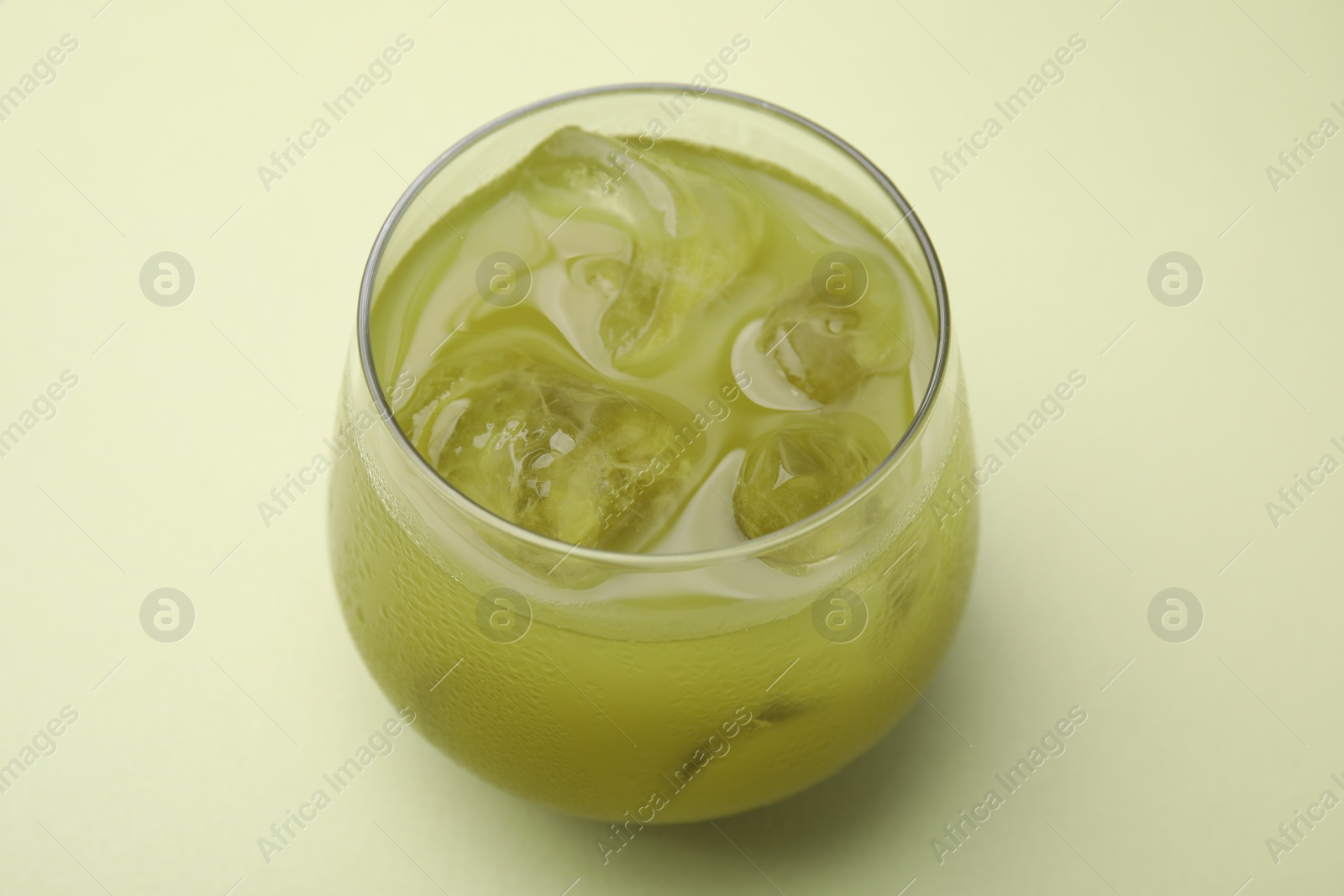 Photo of Glass of delicious iced matcha tea on green background, closeup