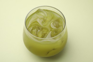 Glass of delicious iced matcha tea on green background, closeup