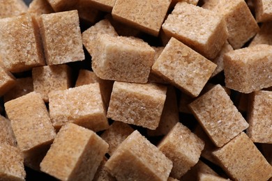 Brown sugar cubes as background, top view