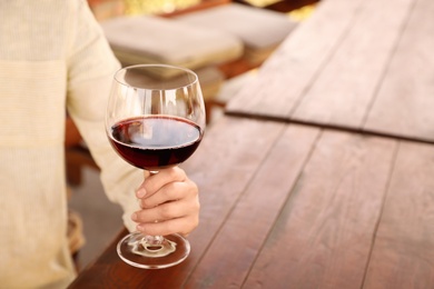 Photo of Woman with glass of red wine in outdoor cafe, closeup. Space for text