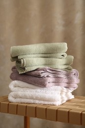 Stack of soft towels on wicker bench indoors