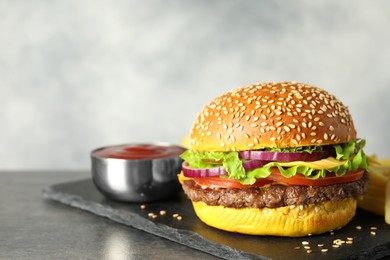 Photo of Burger with delicious patty and sauce on dark table against gray background, closeup